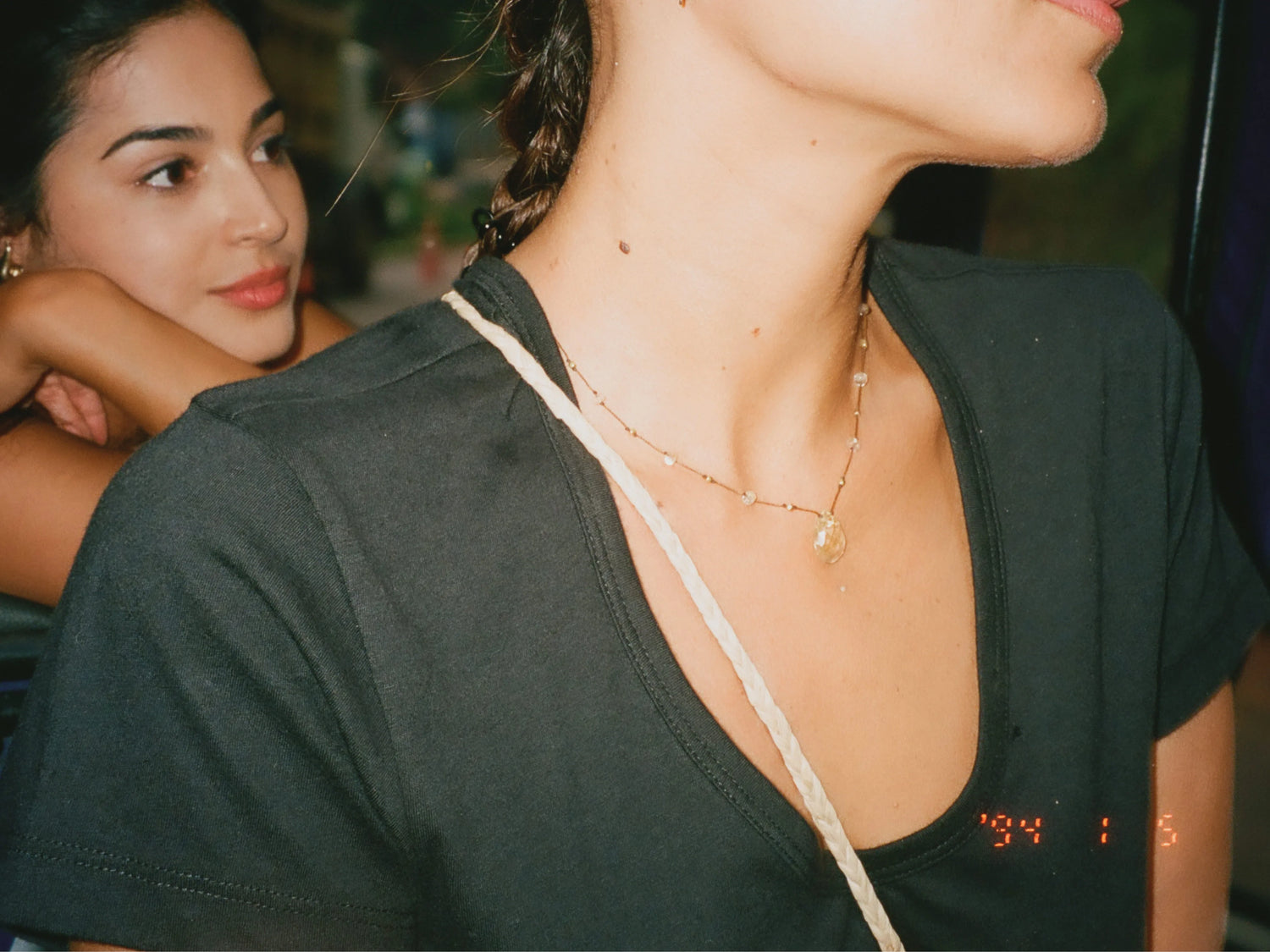 Woman modeling a charcoal V-neck t-shirt, close-up of the neckline and layered necklaces