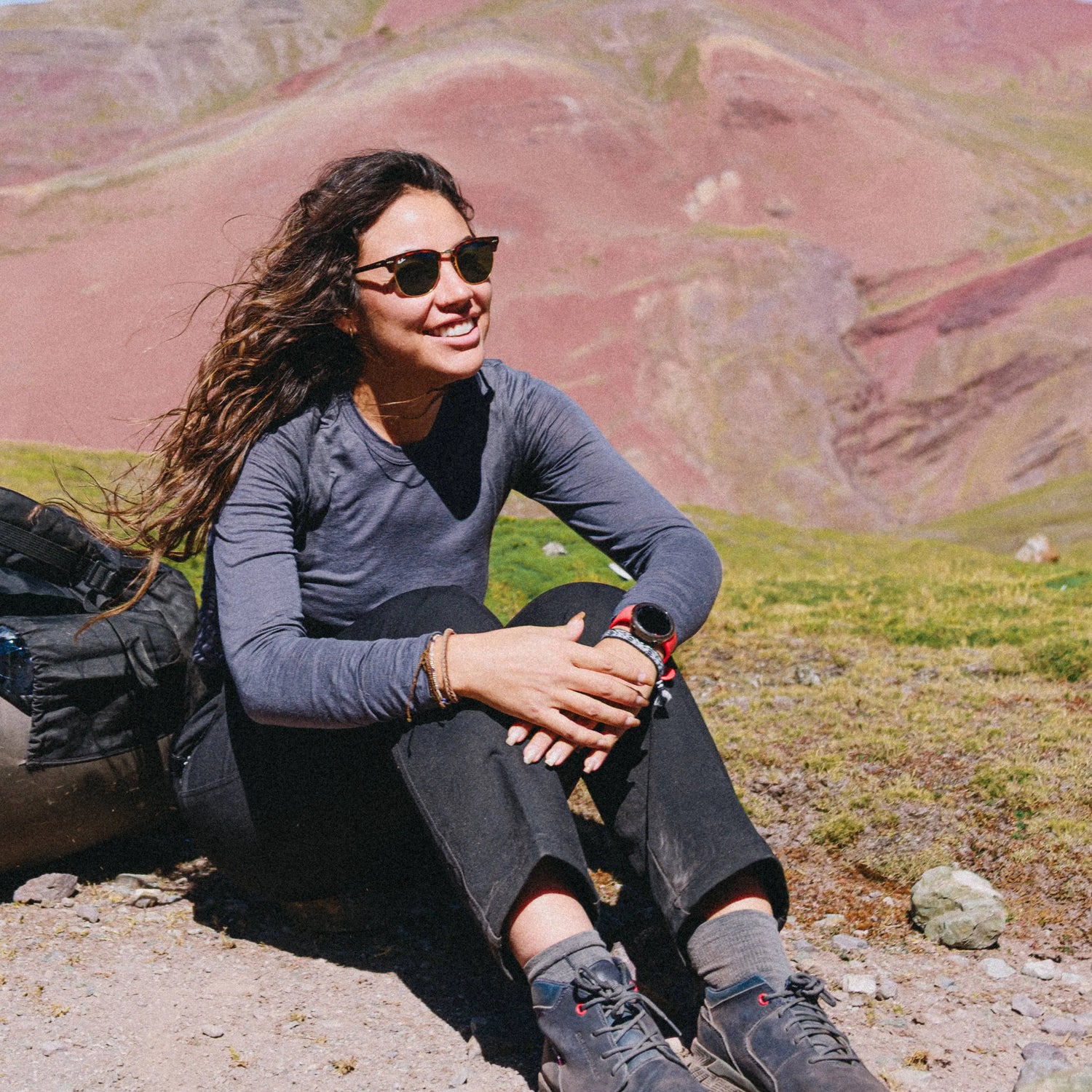 3/4 view of Women’s Aire Long Sleeve in charcoal on seated model showing slim lightweight fit and U-neck, mountain background