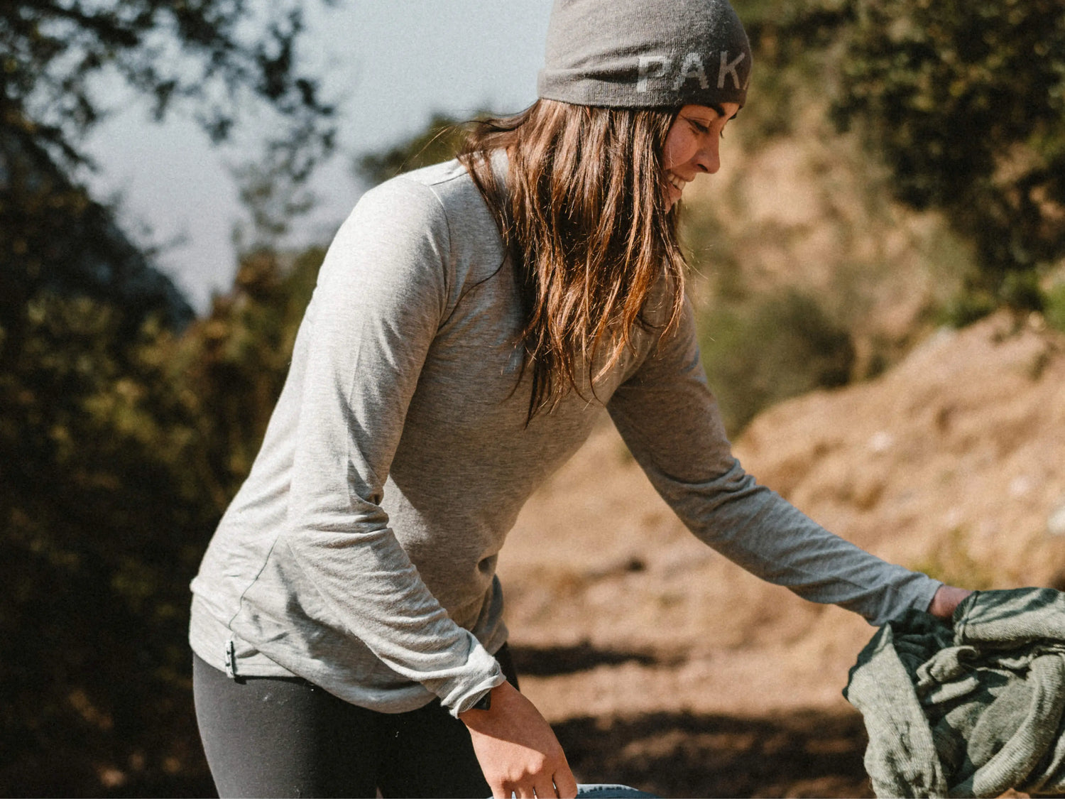 Three-quarter view of Women’s Aire Long Sleeve on a model showcasing fitted lightweight fabric with outdoor trail background