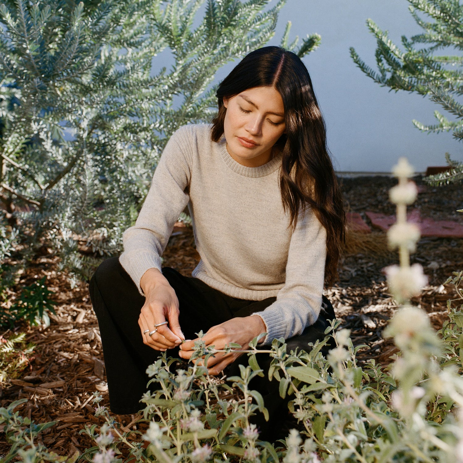 Woman sitting outdoors wearing a light grey Women’s Original Crew alpaca crewneck sweater, relaxed fit