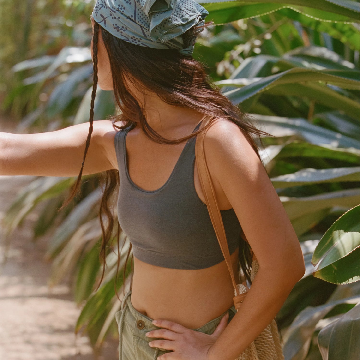 Side view of women’s scoop bralette in charcoal on a model showcasing scoop neckline and slim fit with leafy background