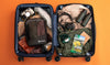 Top-down view of two Upcycled Packing Cubes showing mesh pocket and packed contents inside an open suitcase