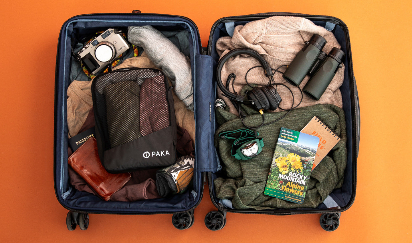 Top-down view of two Upcycled Packing Cubes showing mesh pocket and packed contents inside an open suitcase