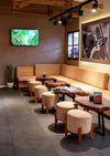 Cozy cafe interior in Cusco with wooden tables, round stools, warm lighting, and framed wall photos