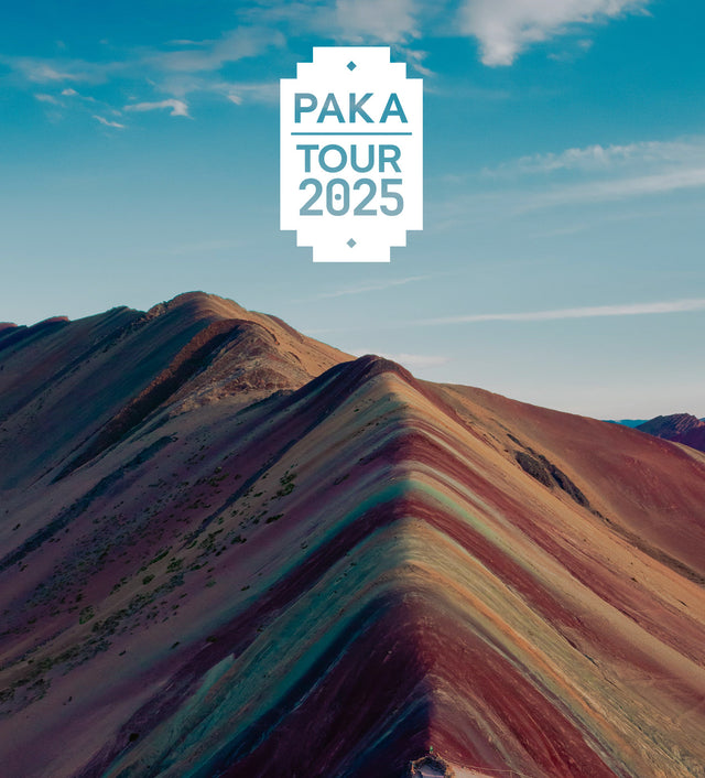 Mountain ridge with colorful layered rock formations and a centered PAKA Tour 2025 badge