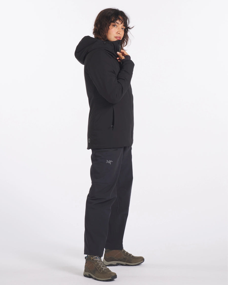 Side view of black Apu Parka with hood and zippered hand pockets, worn in regular fit on white background