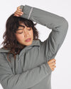 Three-quarter view of gray Apu Parka on model showing zip-front, hood, and thumbhole cuffs on white background