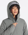 Three-quarter front view of Apu Parka showcasing hood and quilted PAKAFILL insulation with neutral gray background