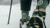 Hiker wearing PAKA performance crew socks and hiking boots on a snowy trail, lower legs and trekking pole visible