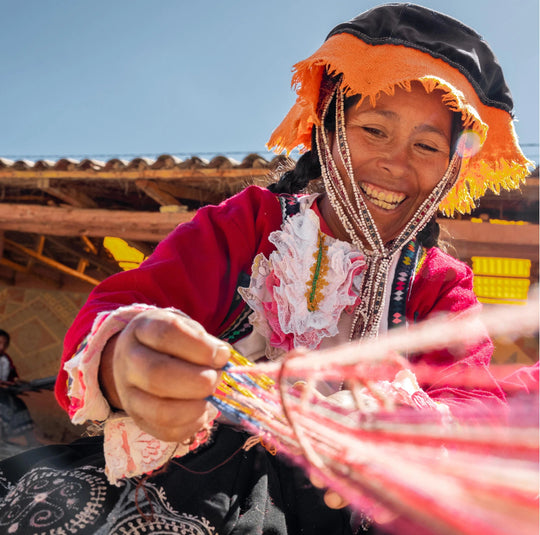 A quechua woman smiling at weaving the alpaca fiber