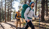 Two smiling backpackers walking in the forest enjoying their alpaca garments