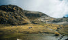 Rocky mountain valley with a shallow lake under a cloudy sky