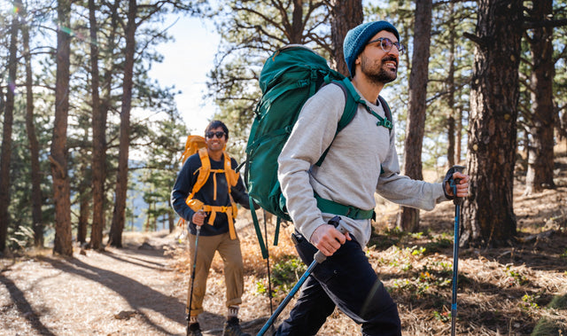 Two smiling backpackers walking in the forest enjoying their alpaca garments
