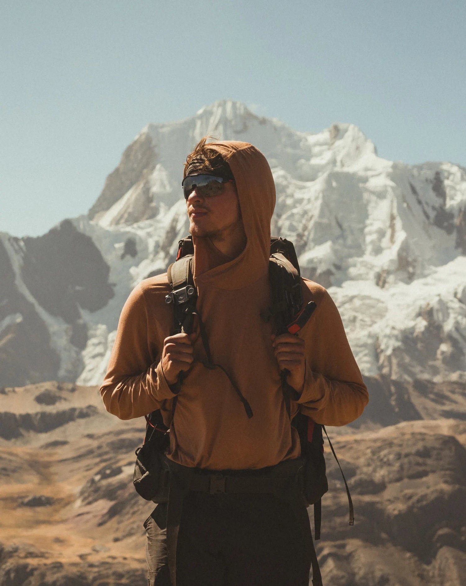 Man Named Ronnie Holding Backpack Straps in Mountains in Camu / Sienna Sol Sun Protection Hoodie – PAKA Apparel