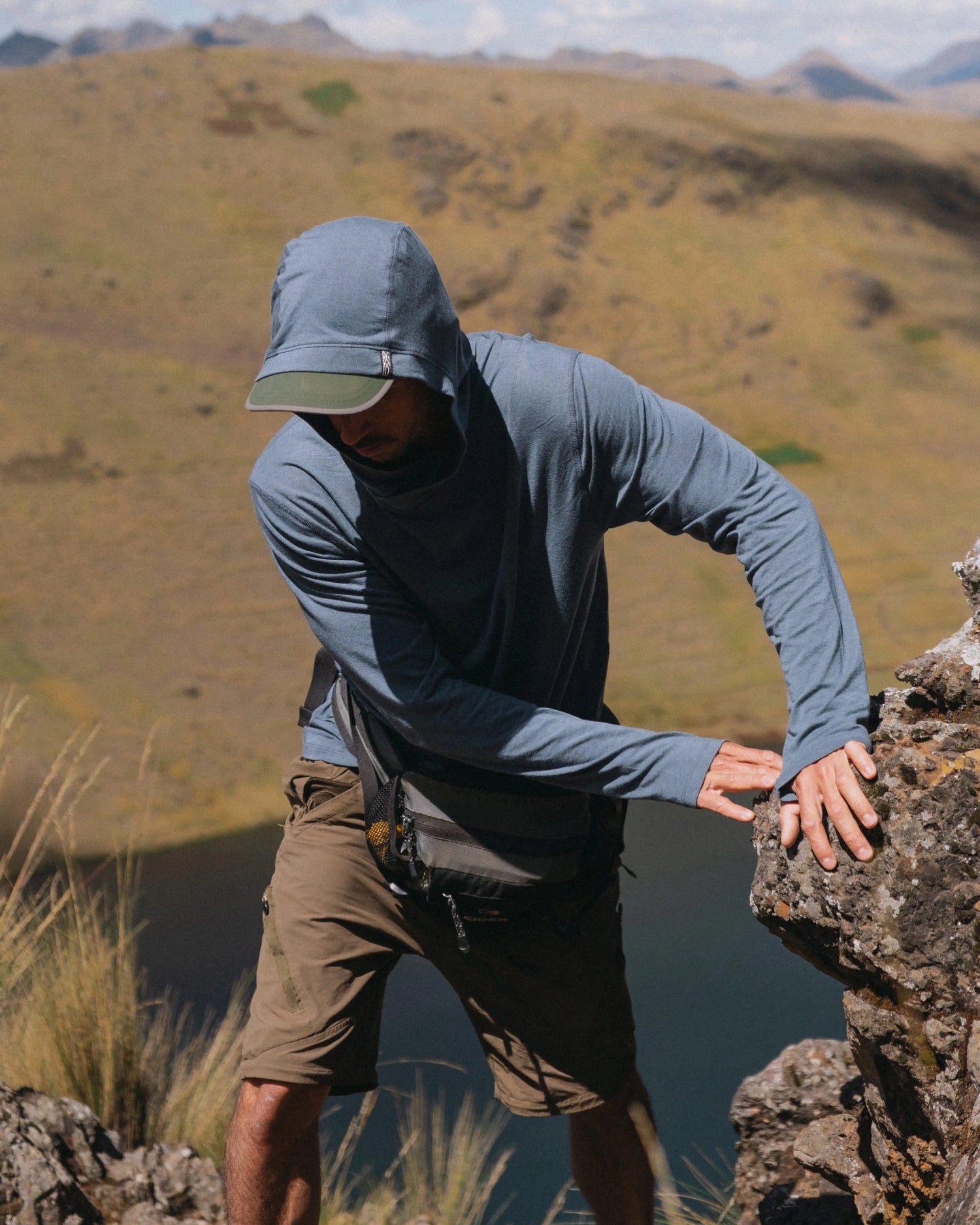 Man Named Gabo Hiking Past Rock in Sol Navy Sun Hoodie for Outdoors – PAKA Apparel