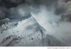 Ausangate summit rising through storm clouds with snow-covered ridges in an aerial mountain landscape
