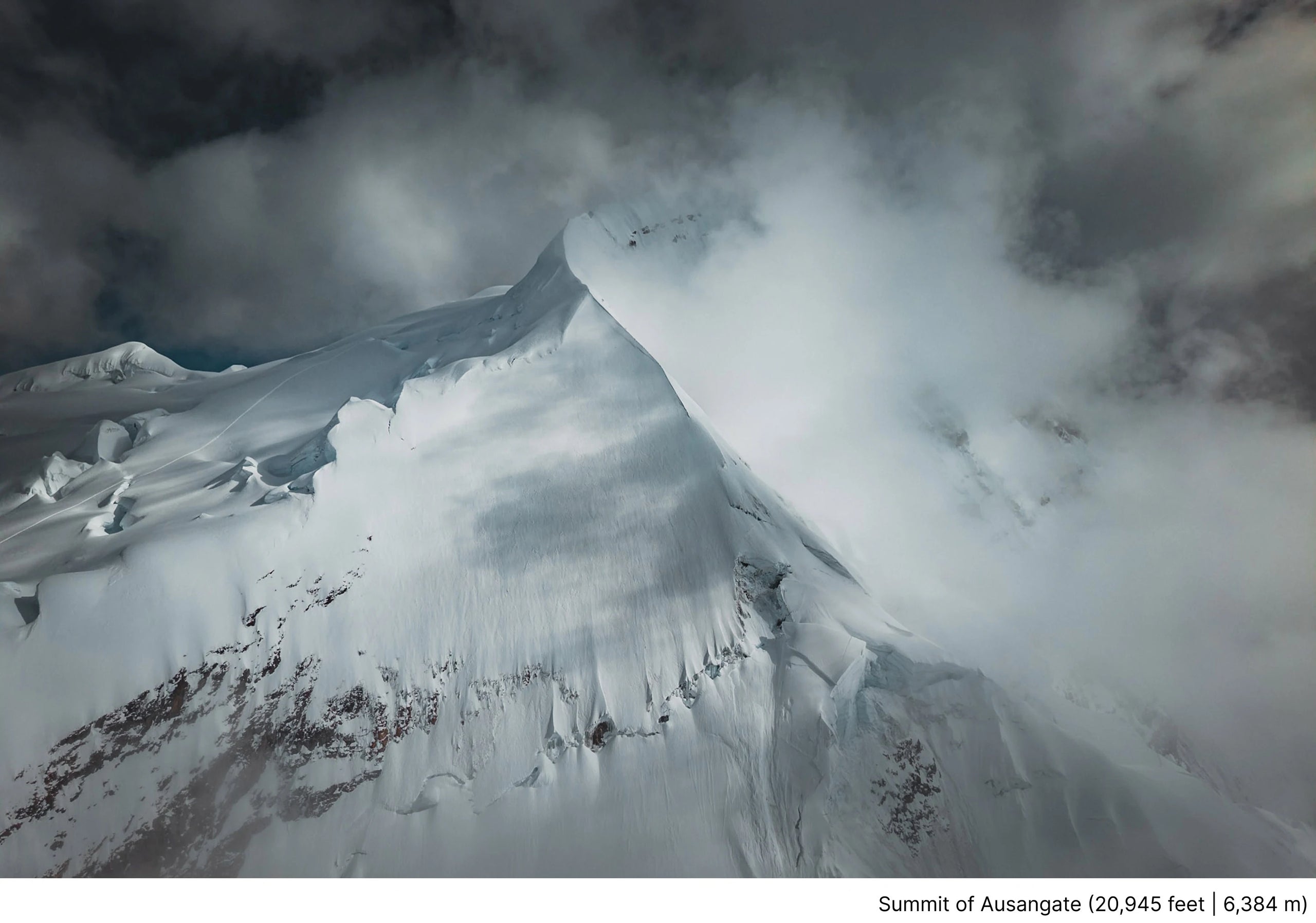 Ausangate summit rising through storm clouds with snow-covered ridges in an aerial mountain landscape