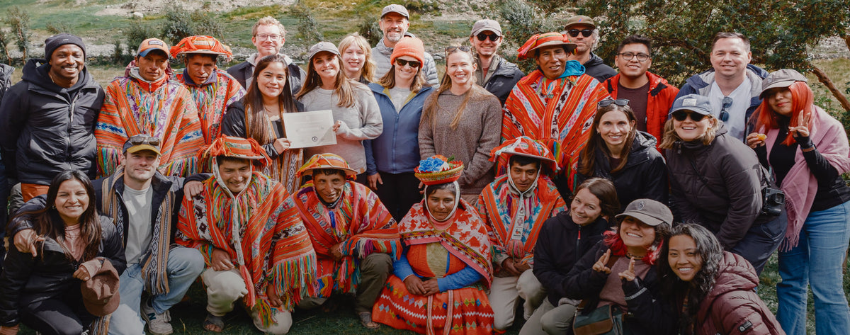 PAKA team and Peruvian artisans posing outdoors in the Andes, wearing colorful traditional garments and PAKA apparel
