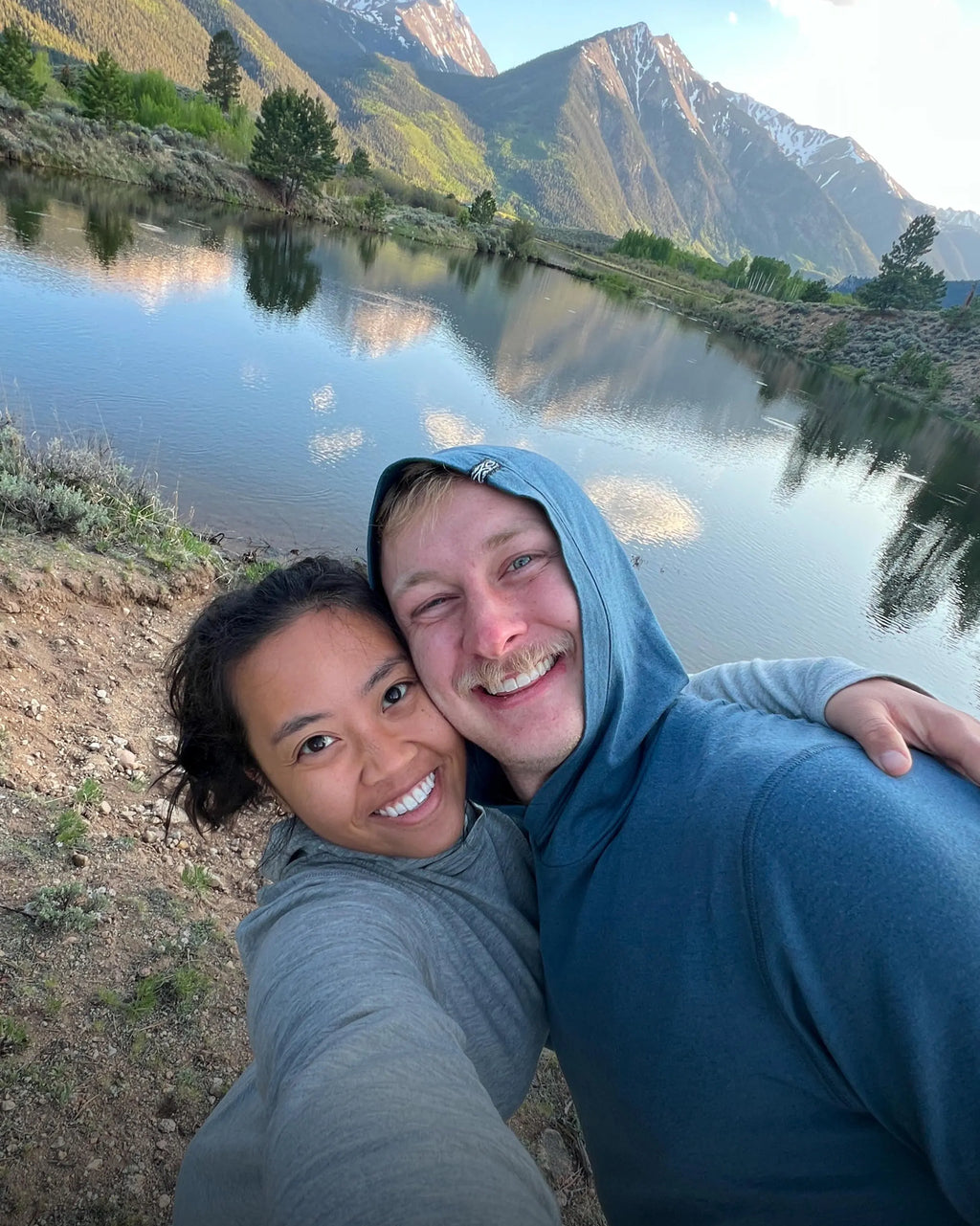 Front view of women’s Sol Hoodie showcasing lightweight alpaca-blend fabric and sun-protective hood with mountain background