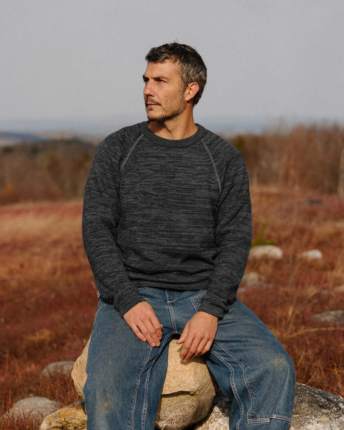 Front view of The Original Crew alpaca crewneck in charcoal showing raglan seams and relaxed fit on model in a field