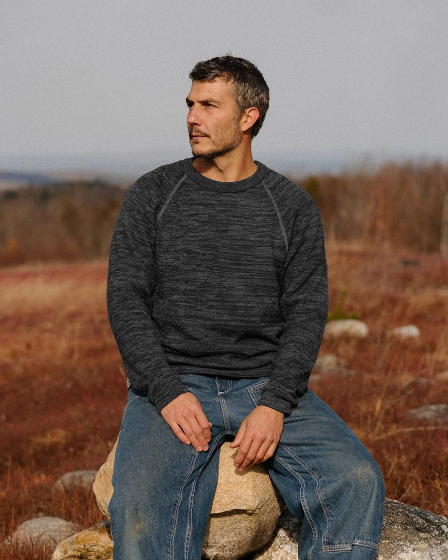 Front view of The Original Crew alpaca crewneck in charcoal showing raglan seams and relaxed fit on model in a field