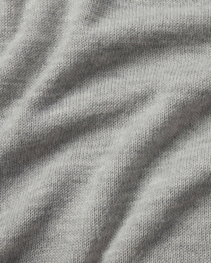 Close-up of The Original Crew alpaca crewneck sweater showing soft light grey knit texture and draped fabric