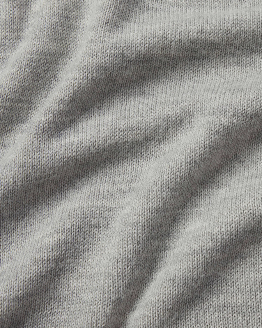 Close-up of The Original Crew alpaca crewneck sweater showing soft light grey knit texture and draped fabric