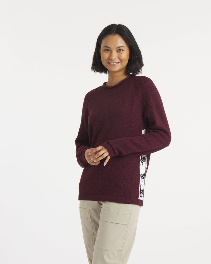 Three-quarter view of The Cusco sweater in burgundy on model showcasing patterned side panels and mock roll neckline on white