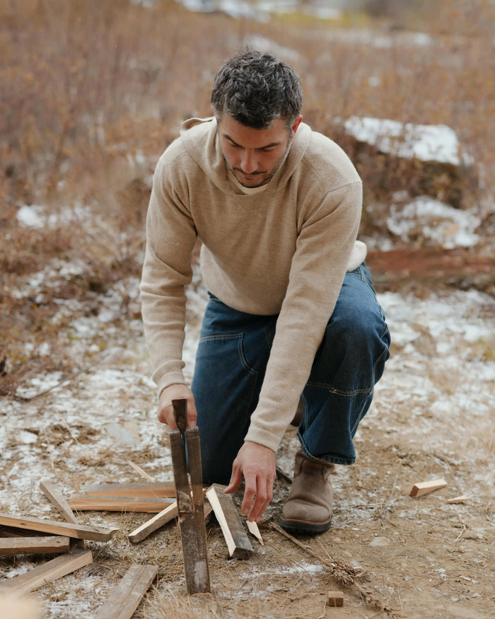 Man Splitting Wood Outdoors in The Hoodie Pebble / Beige Alpaca Sweater with a Hood – PAKA Apparel