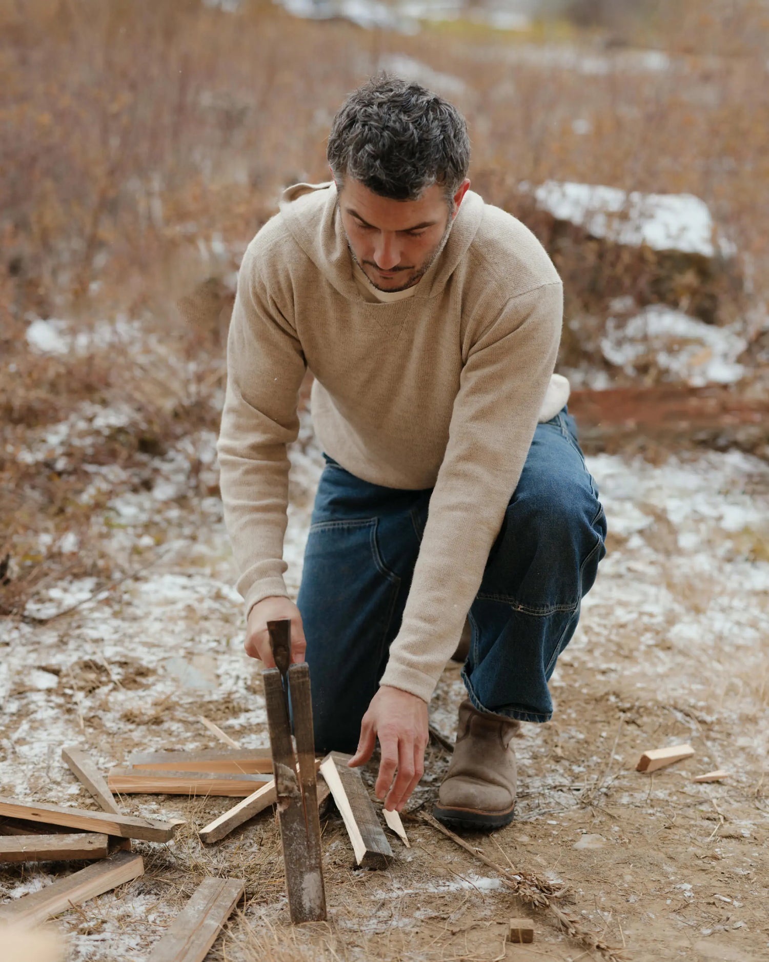 Man Splitting Wood Outdoors in The Hoodie Pebble / Beige Alpaca Sweater with a Hood – PAKA Apparel