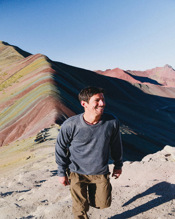 Front of The Lightweight Crew charcoal blue alpaca crewneck showing relaxed fit on model with rainbow mountain backdrop
