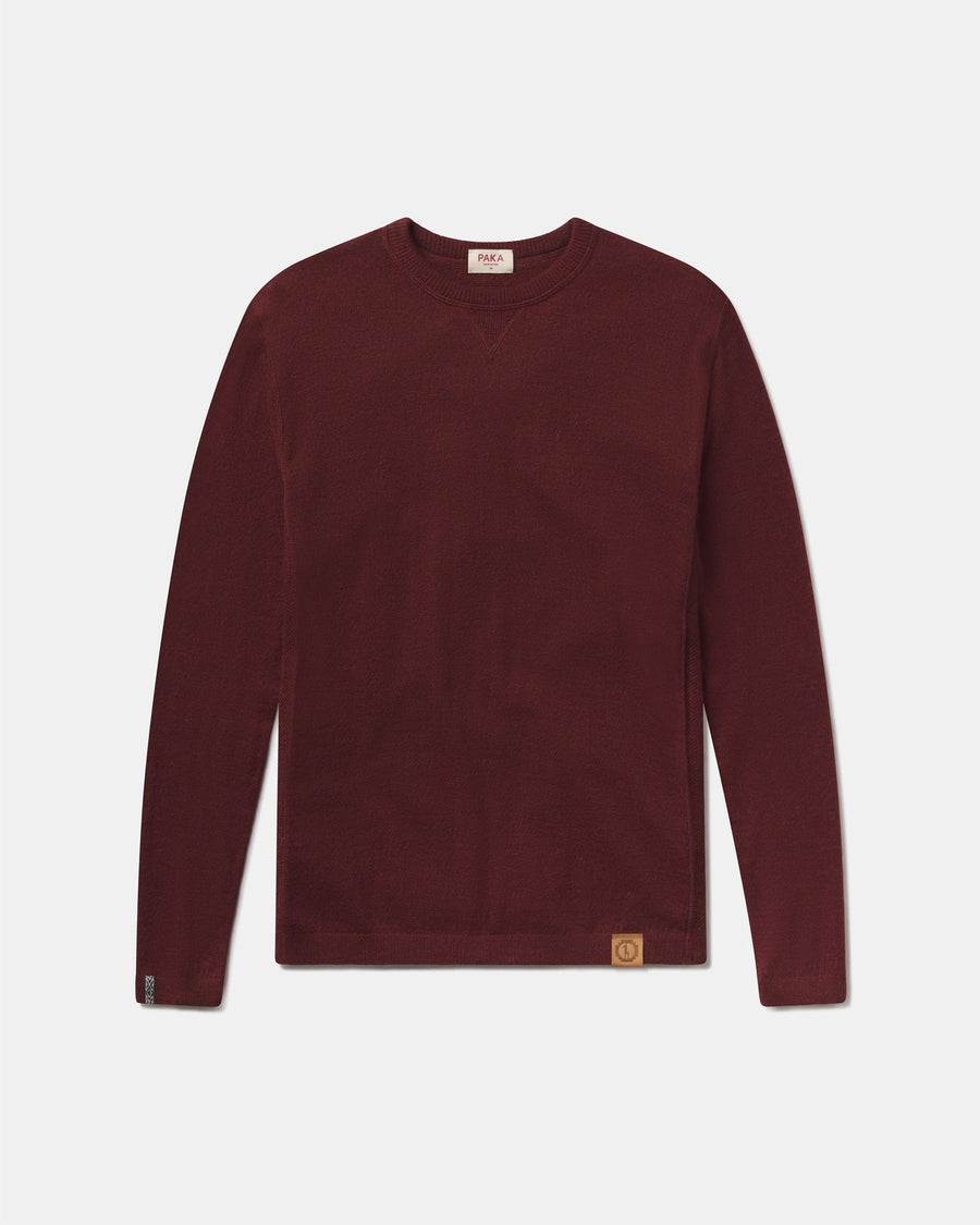 Front view of The Lightweight Crew sweater in burgundy with V-stitch at collar, cuffs and logo patch on gray background