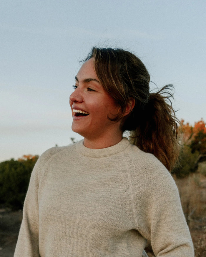 Waist-up view of The Original Crew pebble alpaca wool crewneck sweater, relaxed fit on a smiling woman outdoors