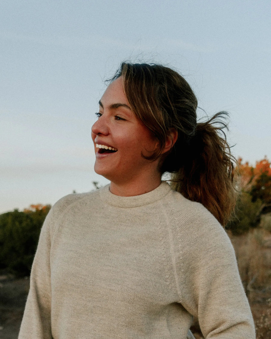 Waist-up view of The Original Crew pebble alpaca wool crewneck sweater, relaxed fit on a smiling woman outdoors
