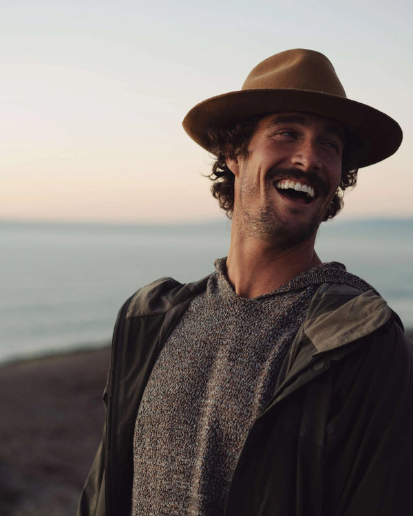 The Vida hoodie in brown marled knit on a model, showing relaxed fit and ergonomic hood at the beach