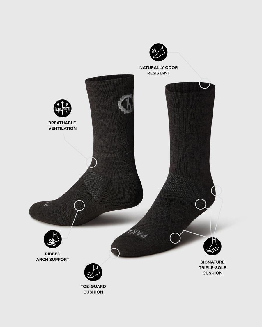 Angled black Trail Crew hiking socks showing vented mesh, ribbed arch support, toe-guard and triple-sole cushion on gray