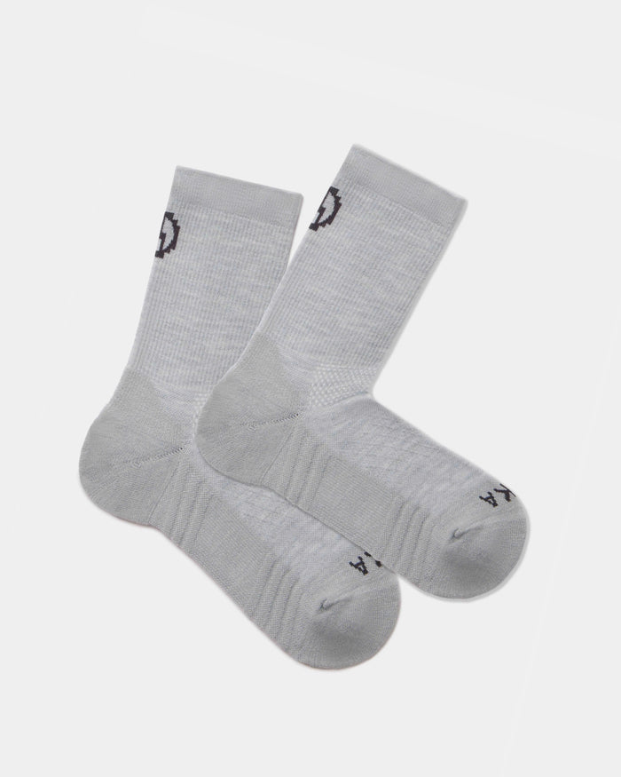 Flat lay of Trail 3/4 crew socks in light gray showcasing cushioned sole and black PAKA logo on cuff and toe on white background