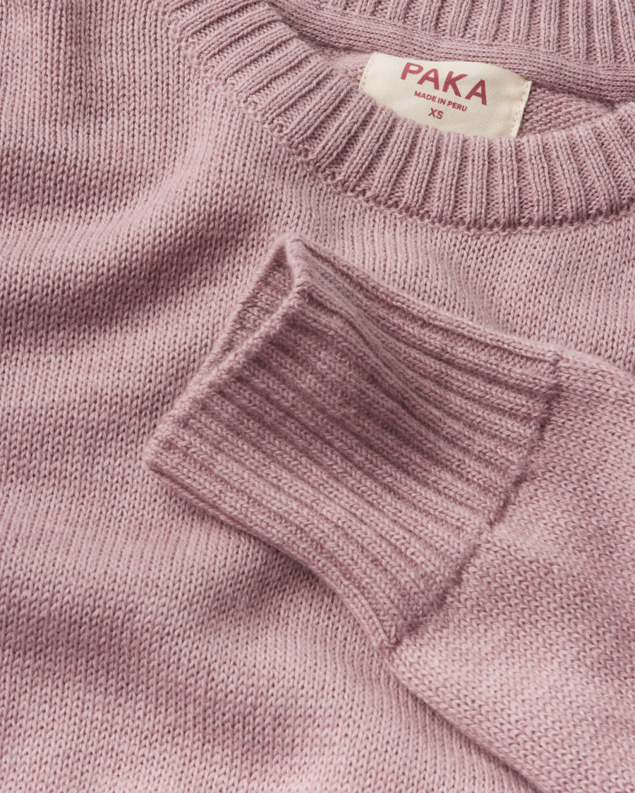 Close-up of Women’s Original Crew alpaca crewneck showing ribbed cuff, knit texture, and PAKA label on woodrose background