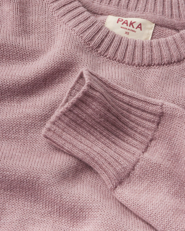 Close-up of Women’s Original Crew alpaca crewneck showing ribbed cuff, knit texture, and PAKA label on woodrose background