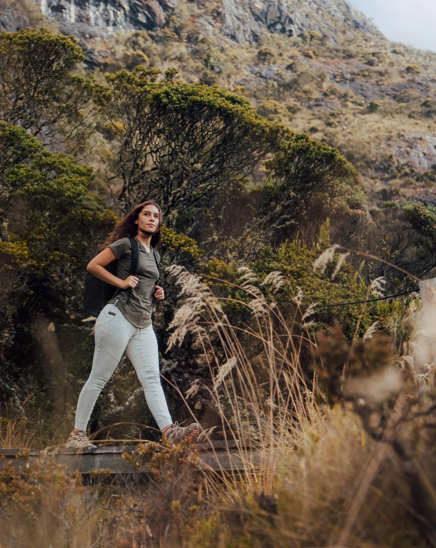 Woman Named Sofia Walking on Wood Dock in Andean Moss / Dark Green Alpaca T-Shirt with Backpack – PAKA Apparel