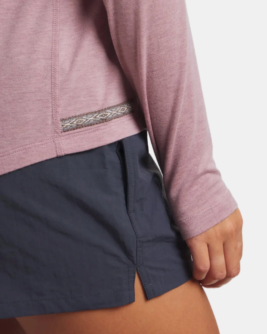 Person wearing a pink long-sleeve shirt and navy shorts on a white background