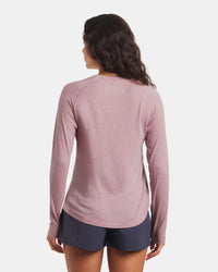 Woman wearing a pink long-sleeve shirt and navy shorts on a white background