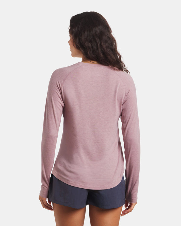 Woman wearing a pink long-sleeve shirt and navy shorts on a white background