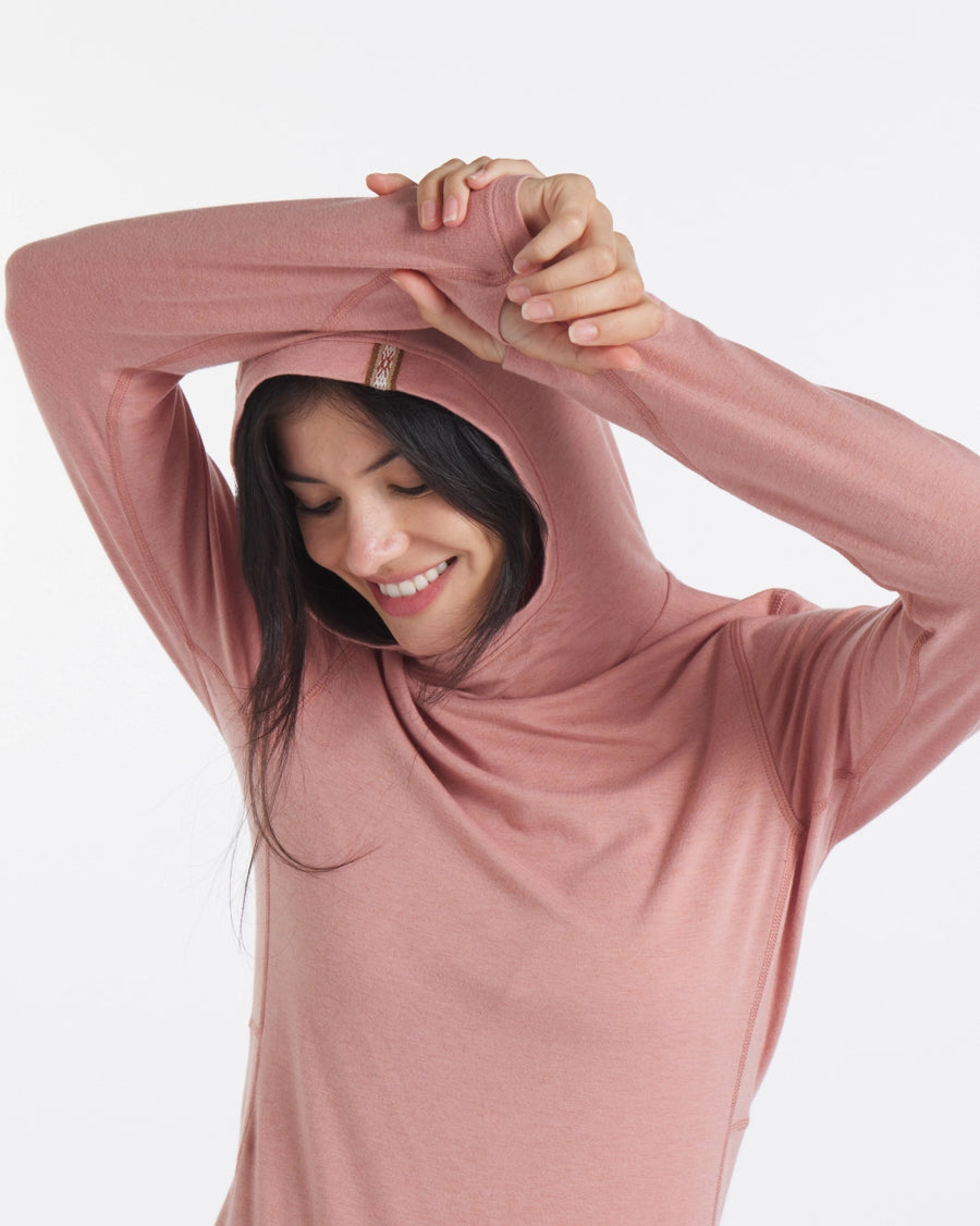 Three-quarter front of Women’s Sol Hoodie in woodrose showing hood up and hidden thumbhole against white background