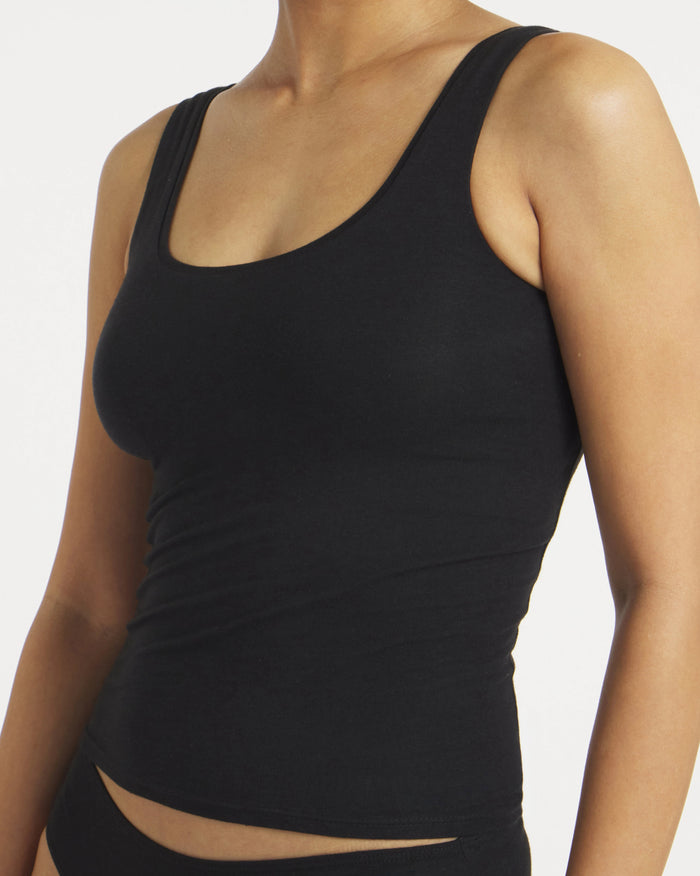 Three-quarter front view of Women’s Essential Tank in black showcasing built-in shelf bra and slim, fitted silhouette on model with plain white background