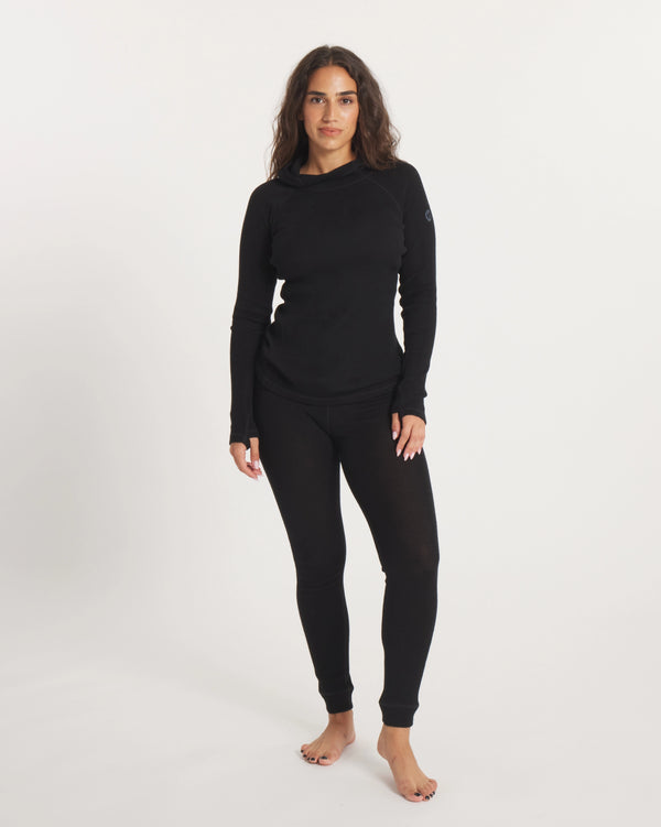 Front view of women’s alpaca thermal baselayer bottoms in black on model showing slim fit and ankle cuffs on light background