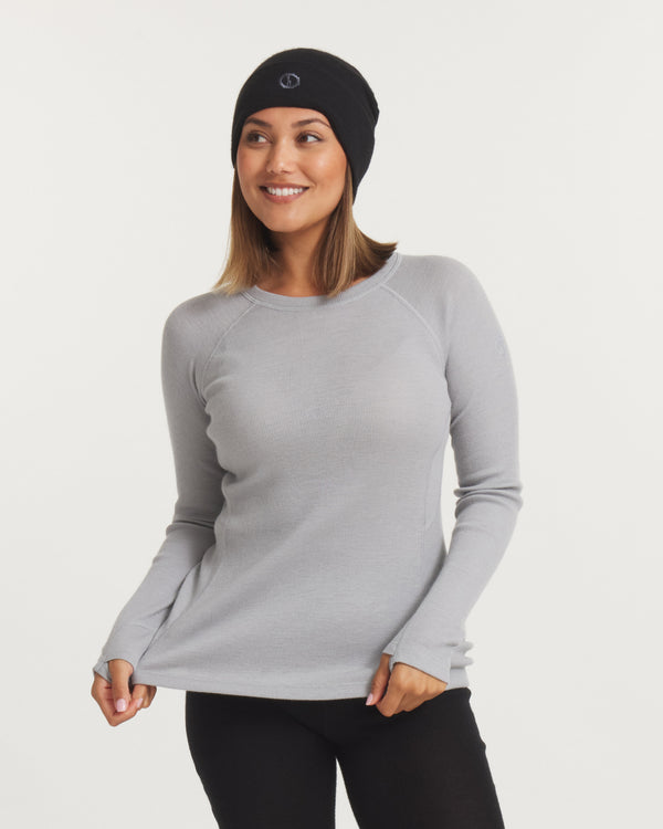 Front view of women’s thermal crew alpaca baselayer top in light gray on model; slim fit, raglan sleeves and thumbholes on white background