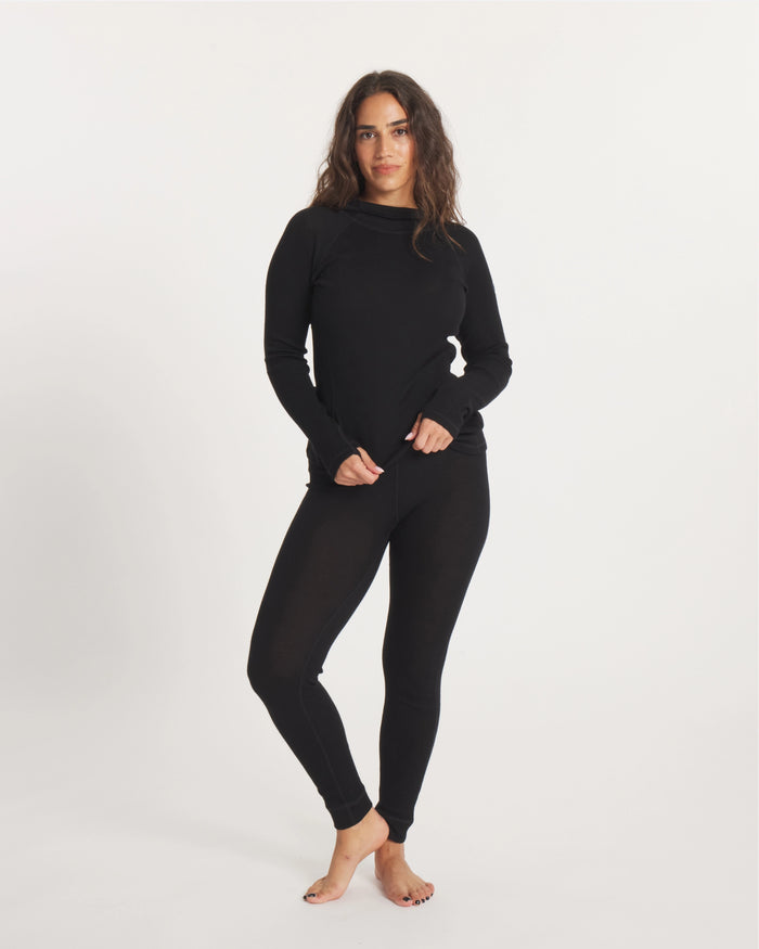 Front view of women’s thermal hoodie, black, slim fit on model, showing hood and thumbhole cuffs on white background