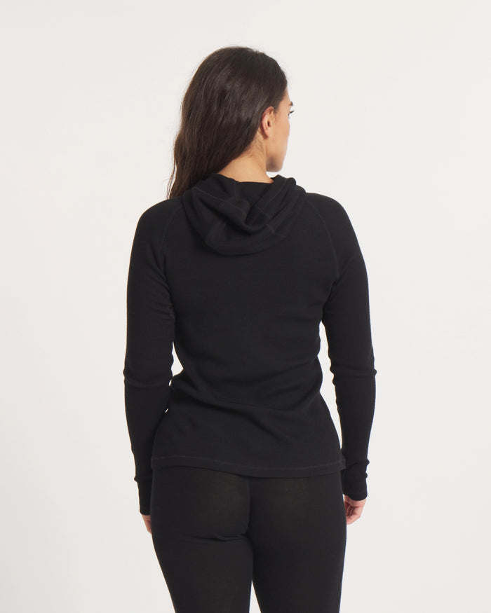 Back view of Women’s Thermal Hoodie in black on model, slim fit showing attached hood and ribbed thermal knit on white background