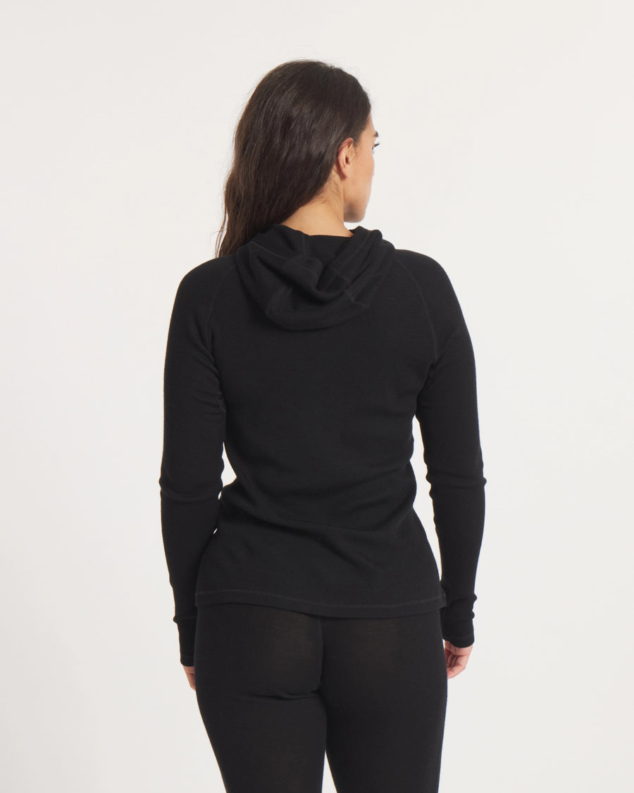 Back view of Women’s Thermal Hoodie in black on model, slim fit showing attached hood and ribbed thermal knit on white background